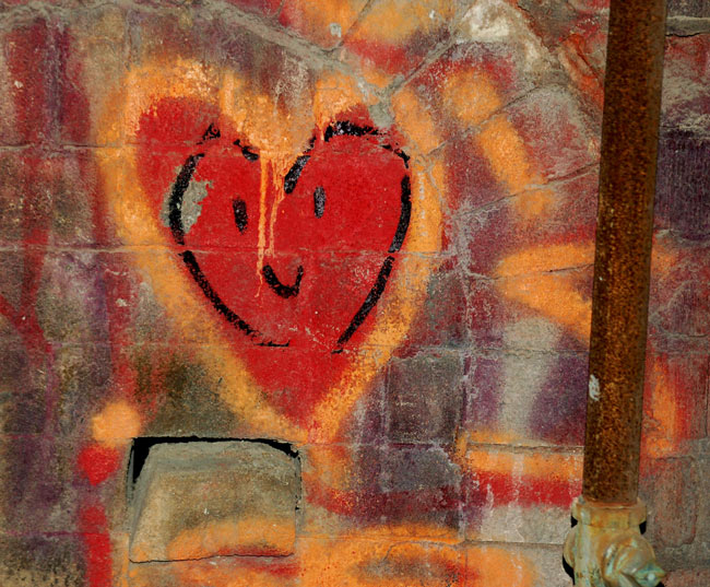 colorful red and orange heart graffiti on on old brick wall