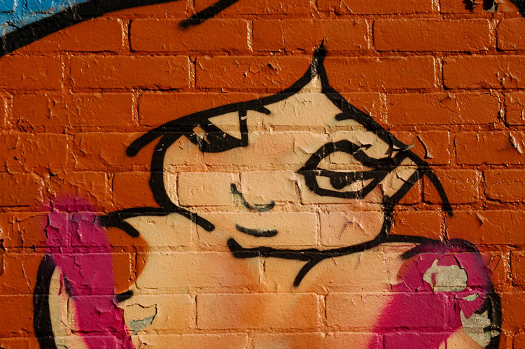 graffiti of a face on a brown brick wall