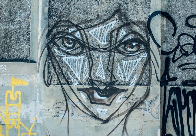 graffiti of a face in blacks and greys on a conrete wall
