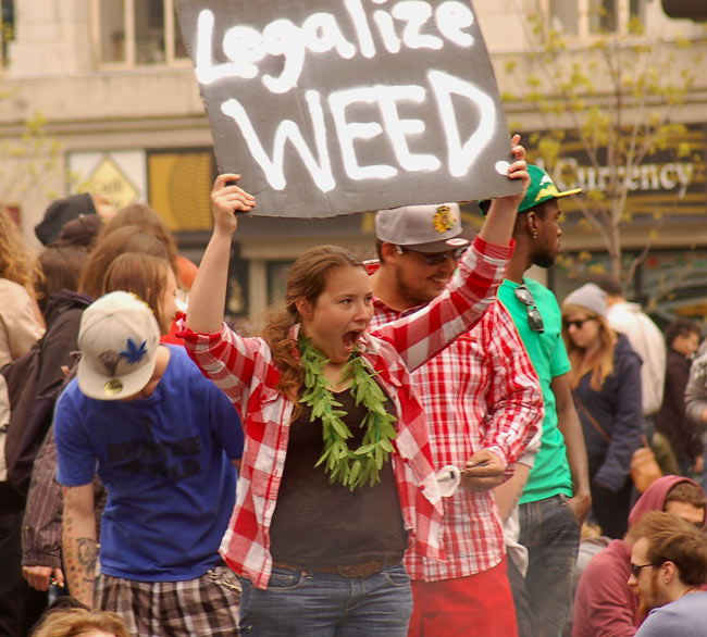 a woman at a protest rally who is holding up a sign that says legalize weed