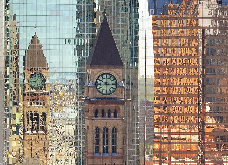 reflections of the old city hall clock tower in the modern glass buildings that are around it