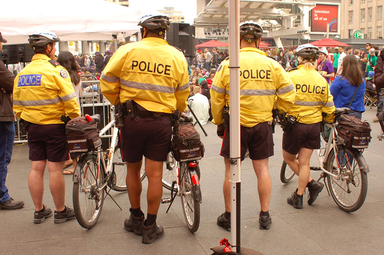 four policemen wearing yellow jackets and standing beside their bikes