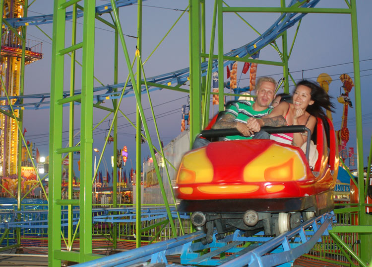 two people riding on a roller coaster as it goes around a corner
