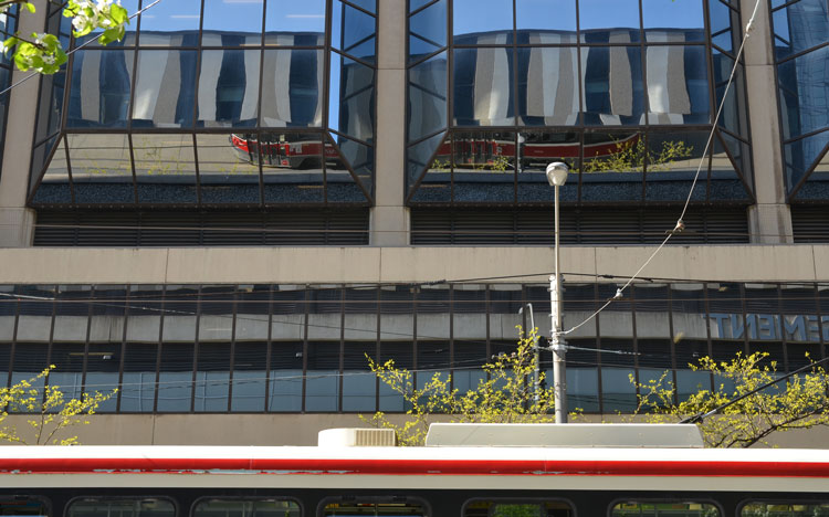 TTC streetcar reflected in the glass of a building on Dundas street