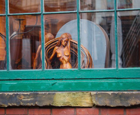 looking through the window of one of the galleries in the Distillery District.  The top part of a statue of a nude woman can be seen