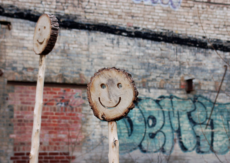 happy faces made out of wood, and on sticks