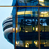 the CN tower peaks out from behind a building with it's interior lights on.  