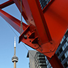 the CN tower is in the distance but it looks like it is under a large red metal sculpture.  