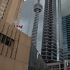 The CN Tower is reflected in a glass window covered building.   