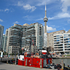 a red and white tug boat is moored on the TOronto waterfront, with the CN tower in the background.  