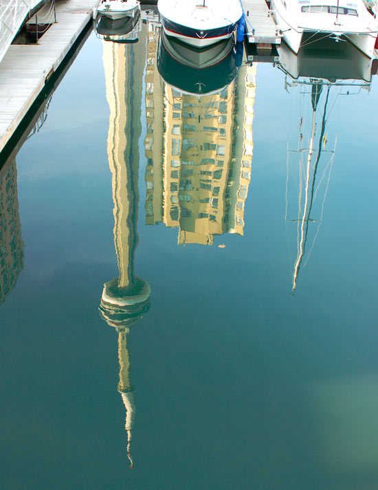 Reflections in the water at harbourfront including boats that are moored there as well as the CN Tower.  