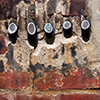 abstract looking picture of an old brick wall.  Several wires that used to exit the building have been cut right at the brick level. 