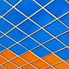 abstract looking picture of a wall covered in blue, turquoise, orange and red square tiles.  Photo taken so the tiles are on a diagonal 