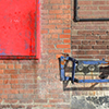 abstract looking picture of the side wall of the old Weston Bakery, red brick building with a number of exterior pipes as well as a large red square section 