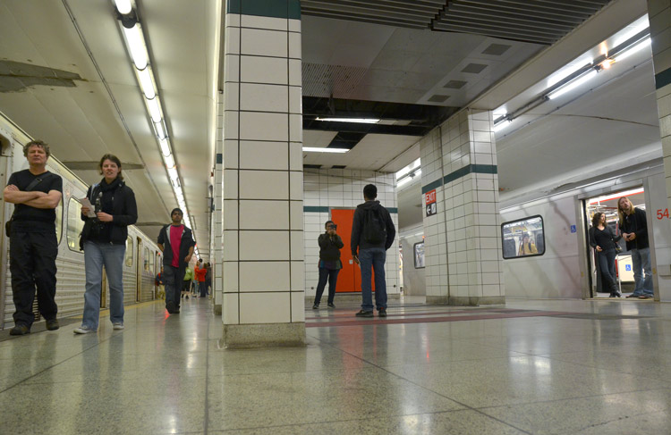 a view of the interior of lower Bay subway station of the TTC, with some people walking on the platform