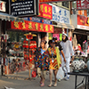 two Asian women in the foreground, walking past Chinese shops on Spadina in Toronto's Chinatown. 