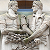 a bas relief sculpture over the door way of a stone building, the Chang School at Ryerson University, of two men from waist up with their arms entwined.  