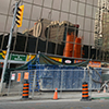 construction on a street in front of a building with reflecting glass, street sign says Duplex Ave, traffic waiting to go through construction area.  