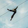 two people are riding high above the camera on a zipline that runs from City Hall to the ground.  City Hall is in the background. 