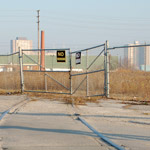 view of the old, unused train tracks that cross Wicksteed Ave but end at a fence and a vacant lot. 