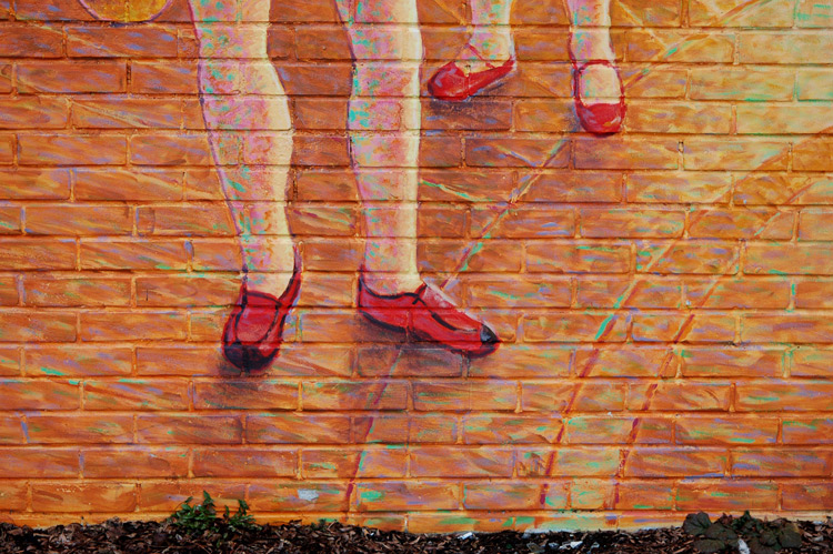 part of a mural. a pair of pink legs with red shoes on the feet