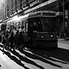 late afternoon, with long shadows, and the setting behind, people getting on a College street TTC streetcar