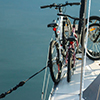 two bicycles tied to the rigging at the front of a sailboat as it is moored in the harbour